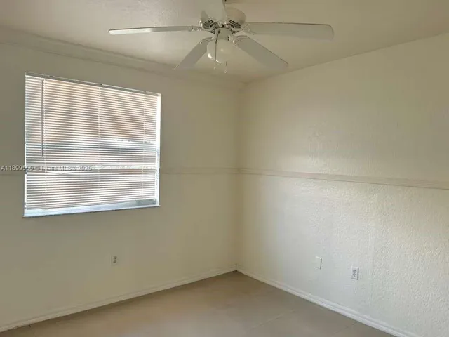 an empty room with a window and a fan