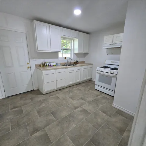 a kitchen with a stove a sink and cabinets