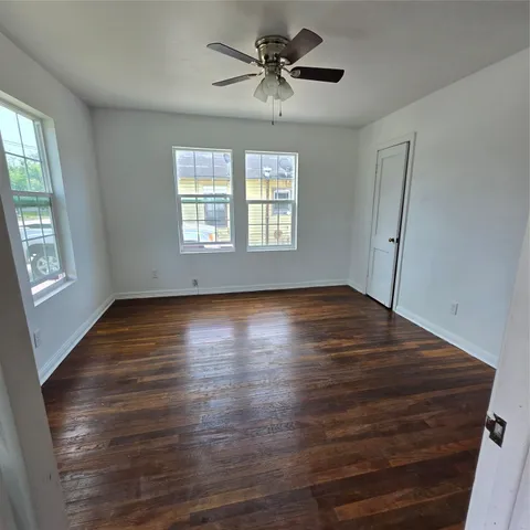 a view of empty room with wooden floor and fan