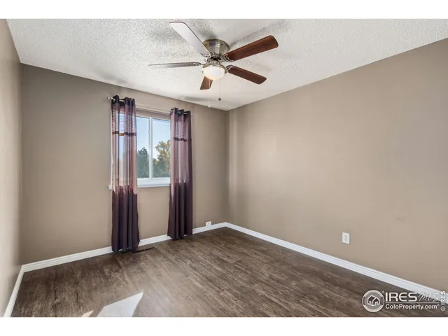 an empty room with wooden floor and ceiling fan