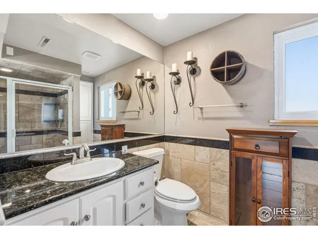 a bathroom with a granite countertop sink mirror vanity and toilet