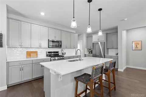 a kitchen with a table a sink cabinets stainless steel appliances and a wooden floor