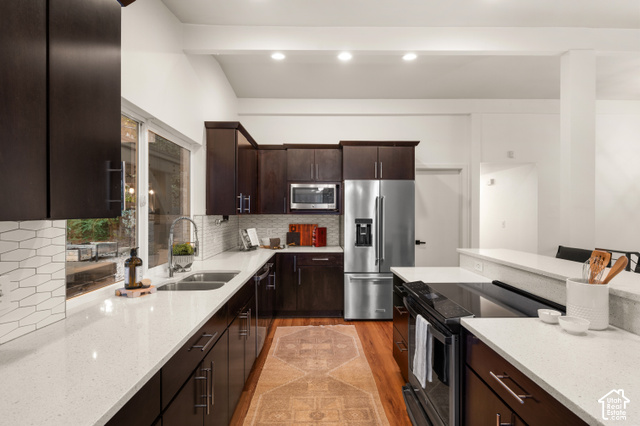 8678 Mount Majestic Road Sandy, UT 84093 - Photo 14 of 37 Kitchen featuring dark wood cabinetry, light-toned countertops, stainless steel appliances, and a tile backsplash