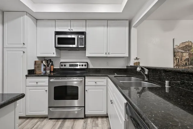 a kitchen with granite countertop white cabinets stainless steel appliances and a sink