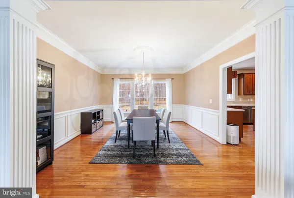 a dining room with chandelier fan and wooden floor