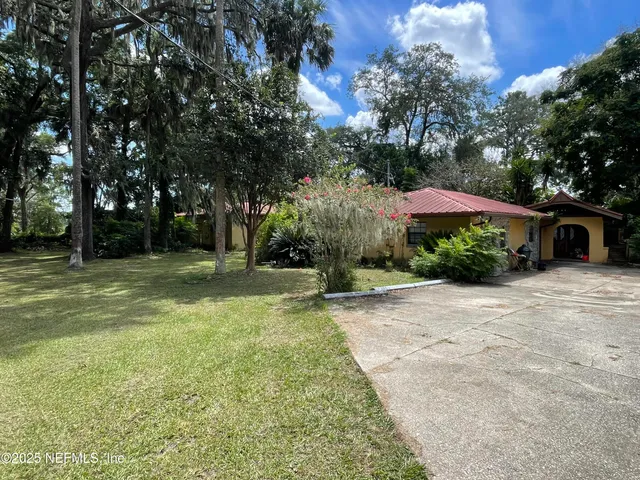 a view of a house with backyard and trees