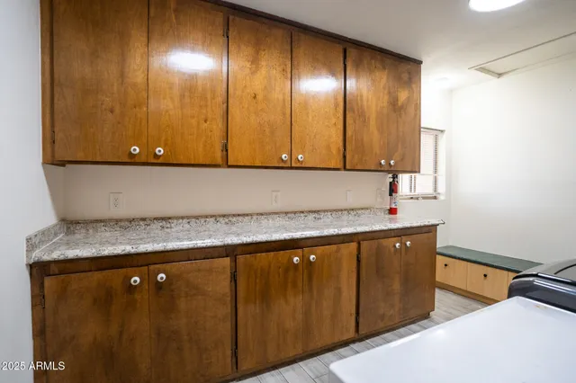 a view of room with kitchen island a sink wooden floor and cabinets