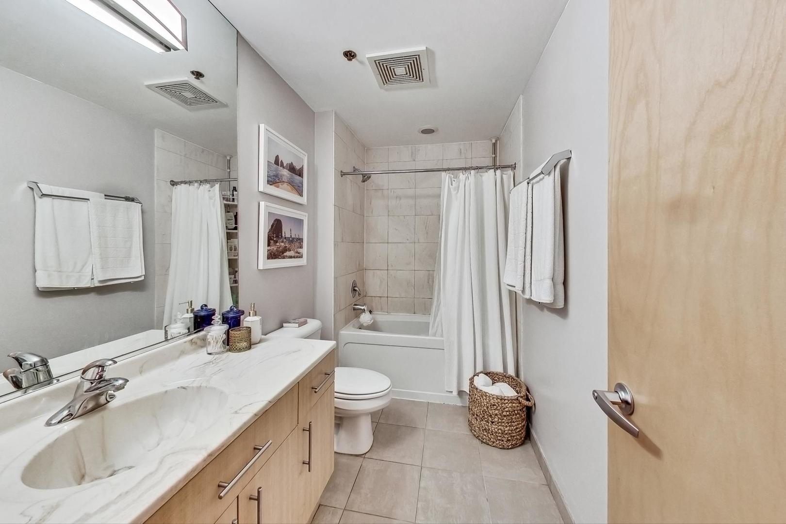 1201 West Adams Street, Unit 609 Chicago, IL 60607 - Photo 14 of 19 a bathroom with a double vanity sink toilet and shower