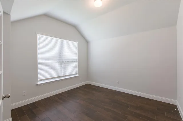an empty room with wooden floor and a window