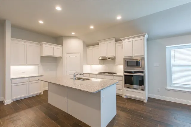 a kitchen with stainless steel appliances granite countertop a stove a sink and white cabinets
