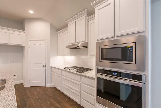 a kitchen with granite countertop cabinets stainless steel appliances and a counter space