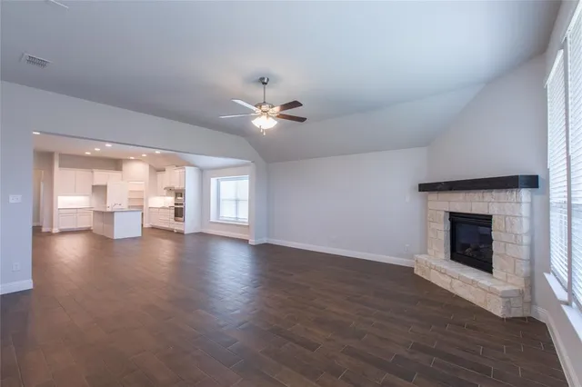 a view of an empty room with wooden floor and a fireplace