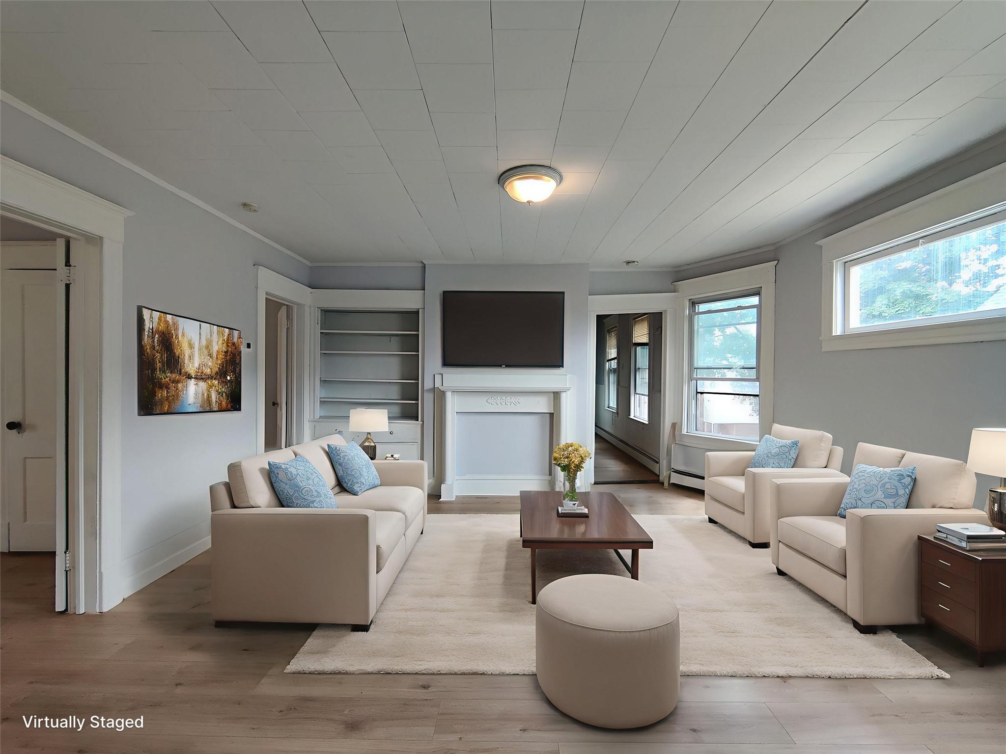 Living room featuring crown molding, built in features, wood finished floors, and a baseboard radiator