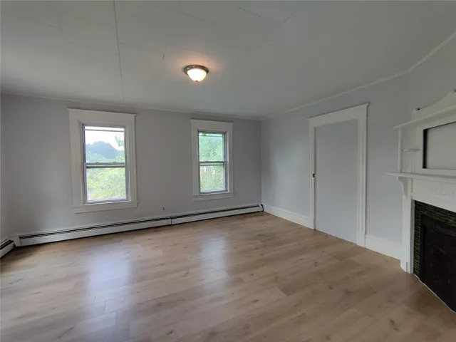 an empty room with wooden floor fireplace and windows