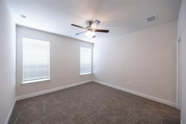 an empty room with windows and fan