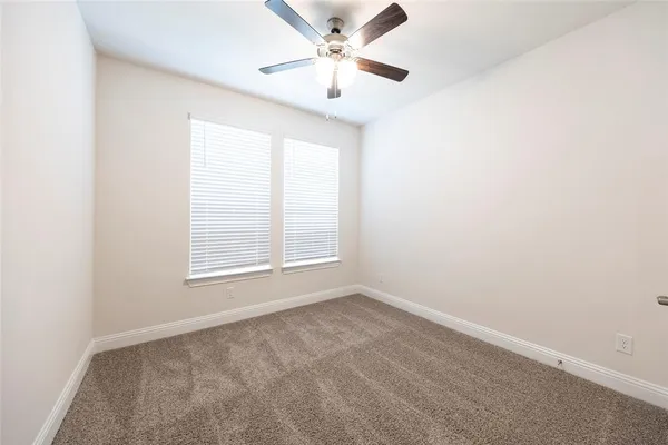 an empty room with a window and a fan
