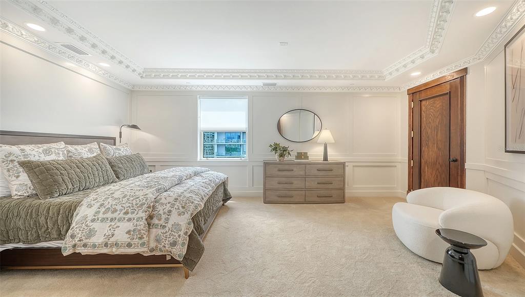 128 Golden Gate Point, Unit 901/1001 Sarasota, FL 34236 - Photo 24 of 55 a bedroom with a bed and chandelier