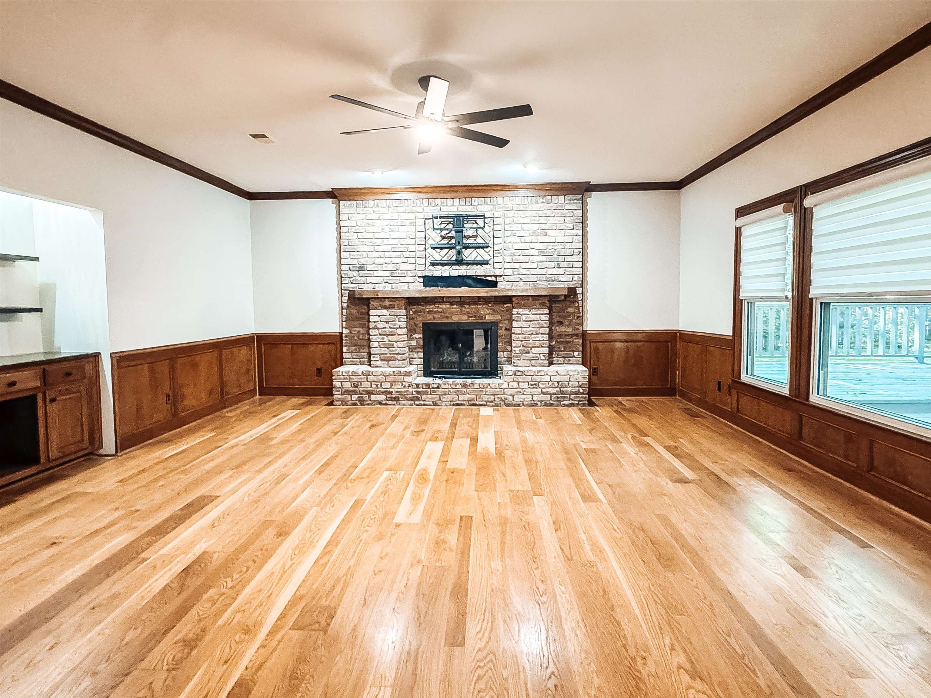 832 South Tree Drive Collierville, TN 38017 - Photo 19 of 40 Spacious room featuring wood-finish flooring, a brick fireplace with a wood mantle, and wainscoting