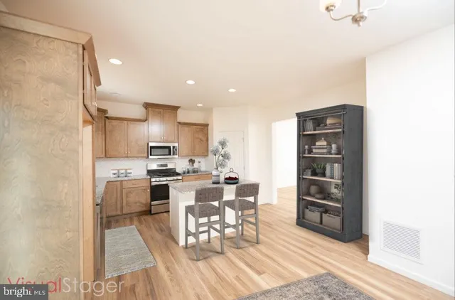 a living room with stainless steel appliances furniture a rug and a kitchen view
