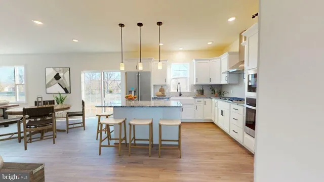 a kitchen with stainless steel appliances kitchen island a table chairs sink and cabinets