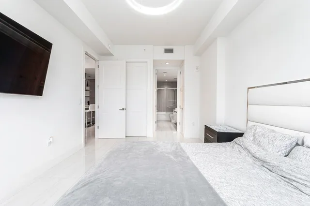 a spacious bedroom with a bed and a flat screen tv