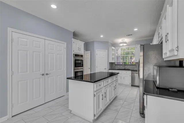 a kitchen with stainless steel appliances granite countertop white cabinets a window and a refrigerator