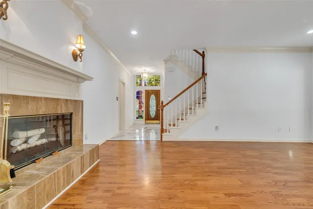 a view of an empty room with wooden floor fireplace and a window