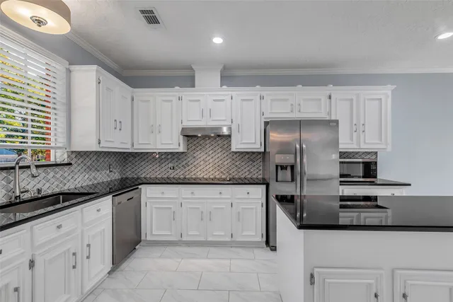 a kitchen with granite countertop a sink and refrigerator