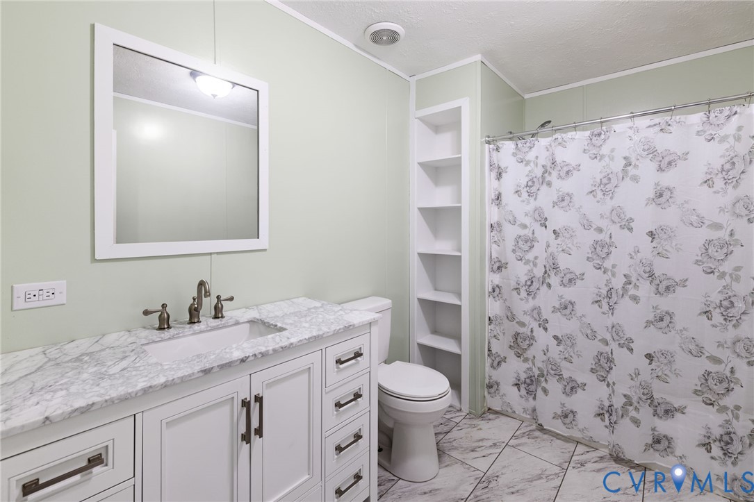 11391 Watkins Road Rockville, VA 23146 - Photo 19 of 28 a bathroom with a granite countertop sink a toilet and a shower