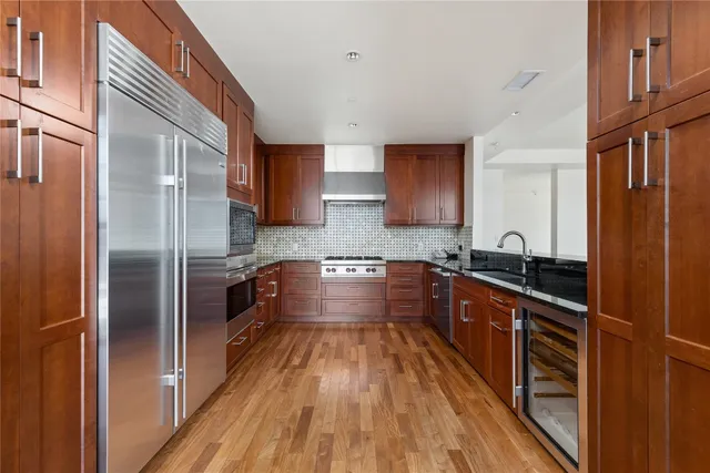 a large kitchen with stainless steel appliances a large counter top a stove and a refrigerator