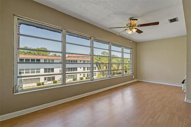 a view of empty room with wooden floor and ceiling fan