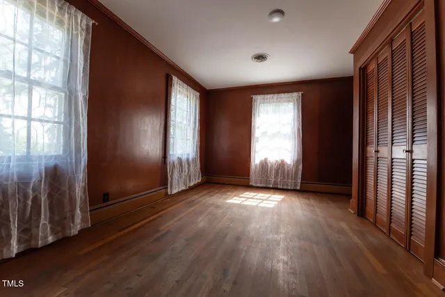 an empty room with wooden floor and windows