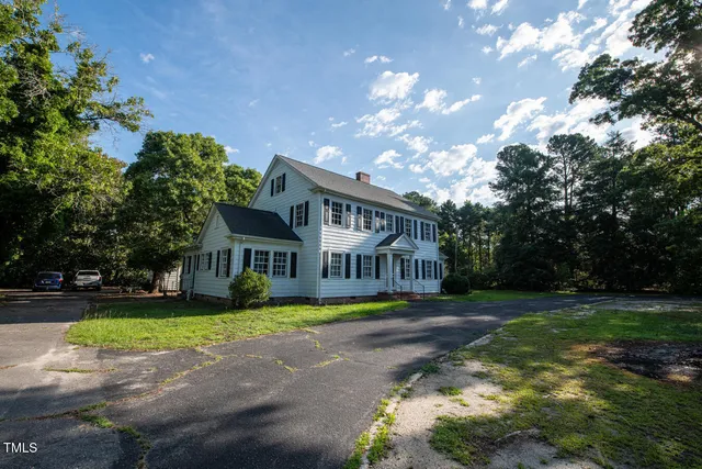 a view of a big house with a big yard and large trees