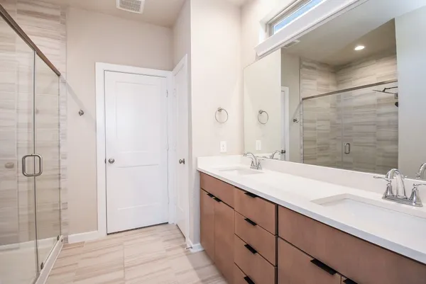 a bathroom with a double vanity sink mirror and shower