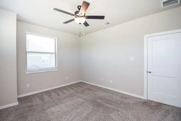 an empty room with a window and a fan
