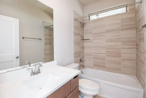 a bathroom with a bathtub shower sink vanity mirror and toilet