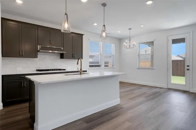 a kitchen with stainless steel appliances granite countertop a sink a stove and a wooden floors
