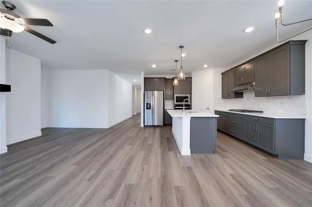 a large kitchen with stainless steel appliances kitchen island a large counter top and a stove top oven