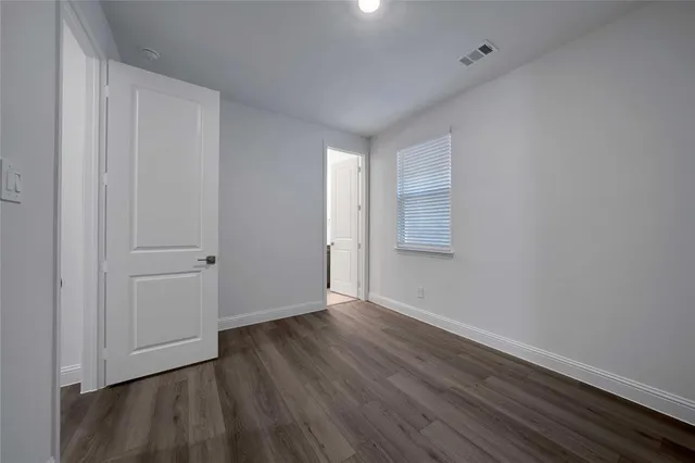 a view of an empty room with closet and wooden floor