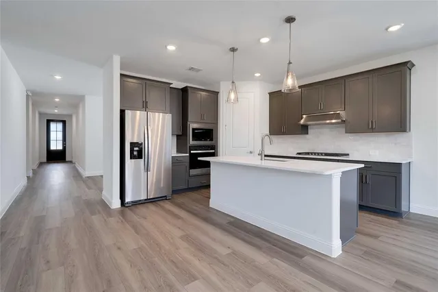 a kitchen with stainless steel appliances granite countertop a refrigerator a sink a stove and a oven