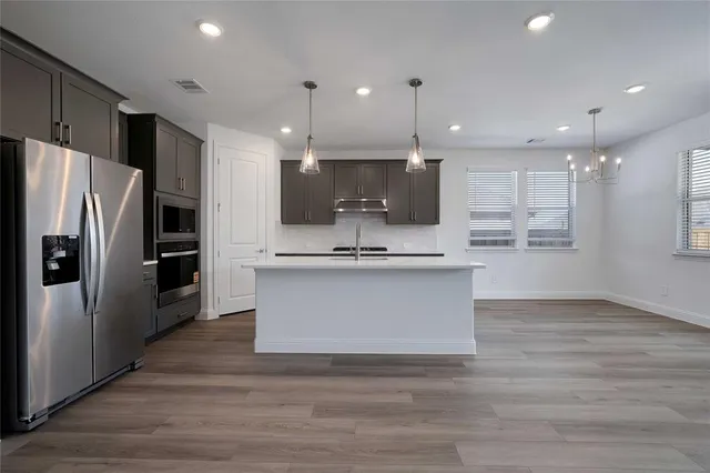 a view of kitchen with kitchen island stainless steel appliances refrigerator stove microwave and cabinets