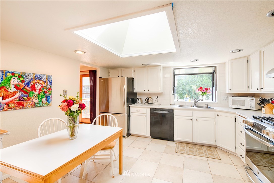 7902 211th Place Southwest Edmonds, WA 98026 - Photo 27 of 33 a kitchen with stainless steel appliances kitchen island granite countertop a sink dishwasher and white cabinets with wooden floor
