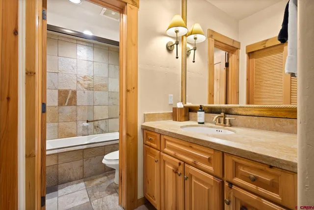 a bathroom with a double vanity sink toilet mirror and shower