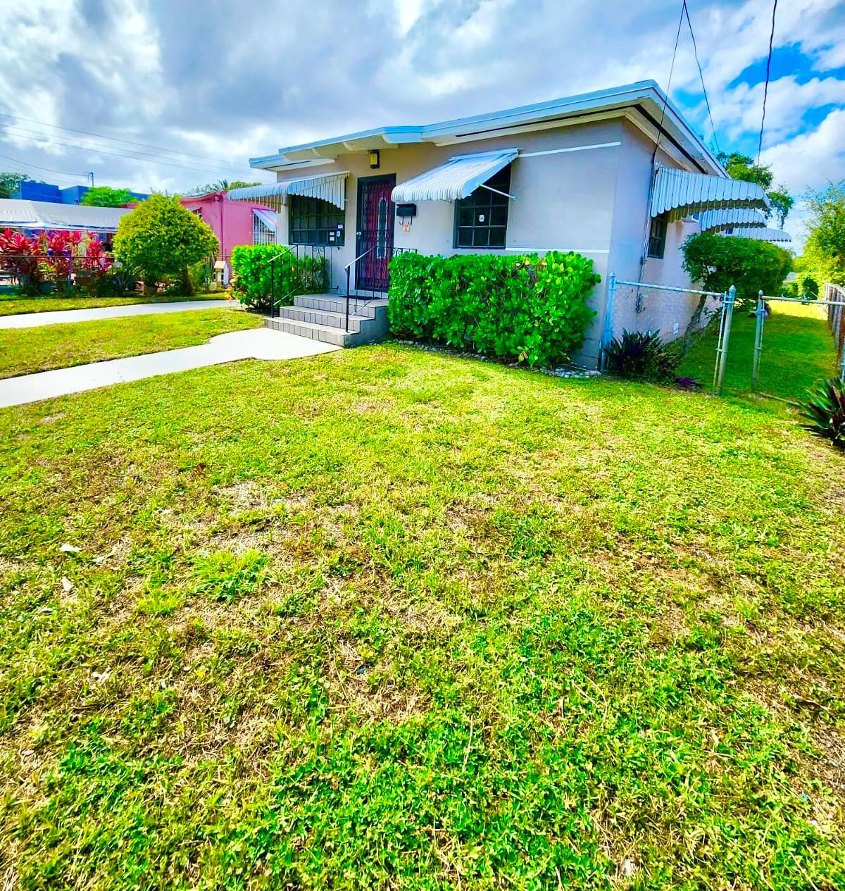 a view of a house with a yard and potted plants