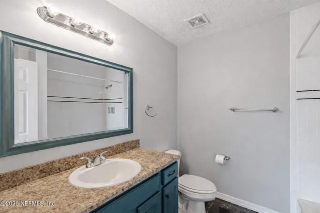 a bathroom with a granite countertop sink toilet a mirror and shower