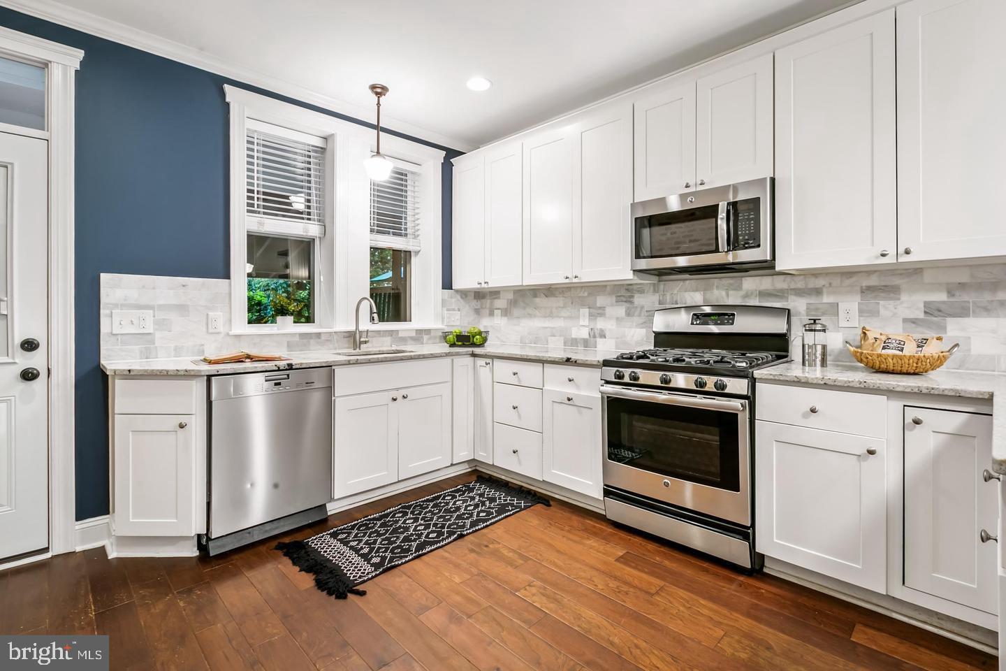 3019 Keswick Road Baltimore, MD 21211 - Photo 5 of 29 a kitchen with stainless steel appliances white cabinets a sink a stove a microwave and wooden floors