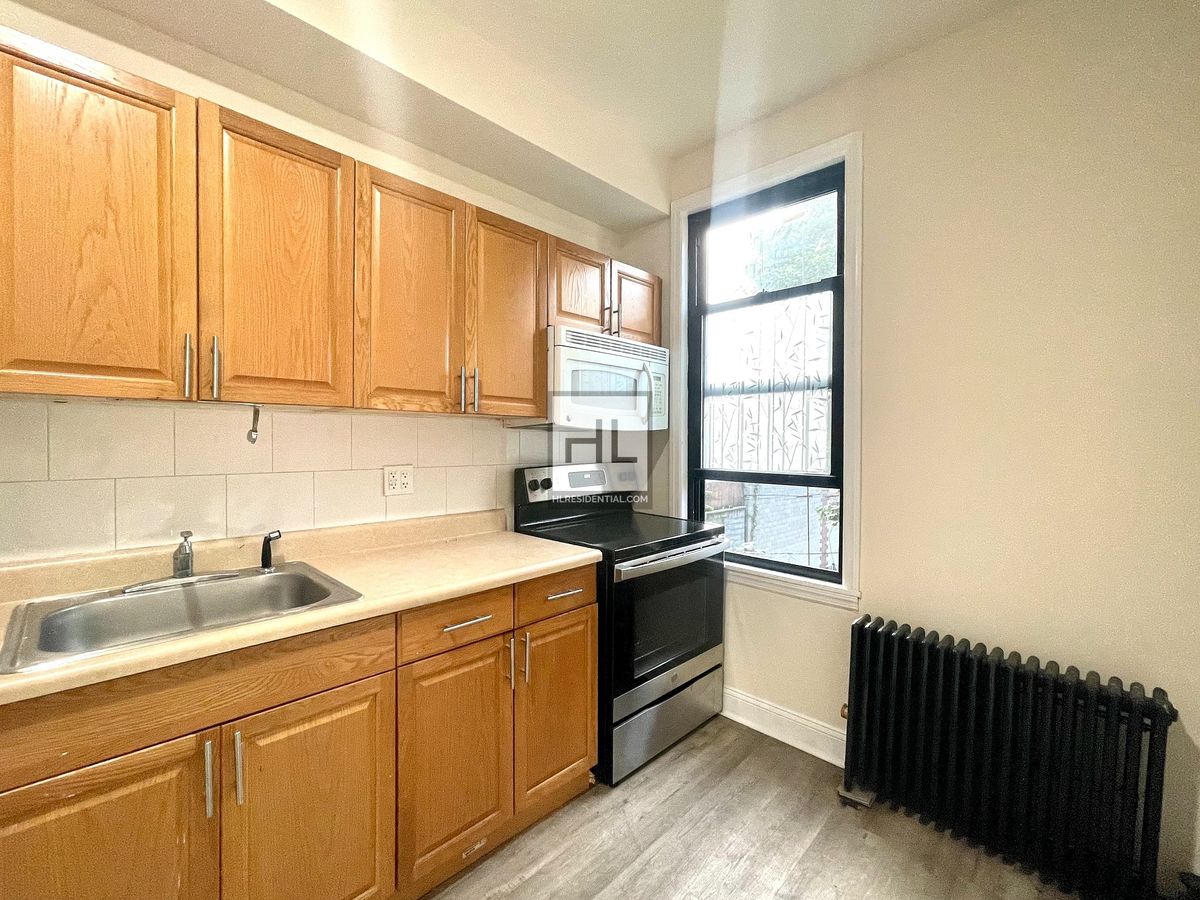 51-28 35th Street, Unit 2 Queens, NY 11101 - Photo 6 of 7 a kitchen with stainless steel appliances granite countertop a sink dishwasher a stove and a refrigerator with wooden cabinets