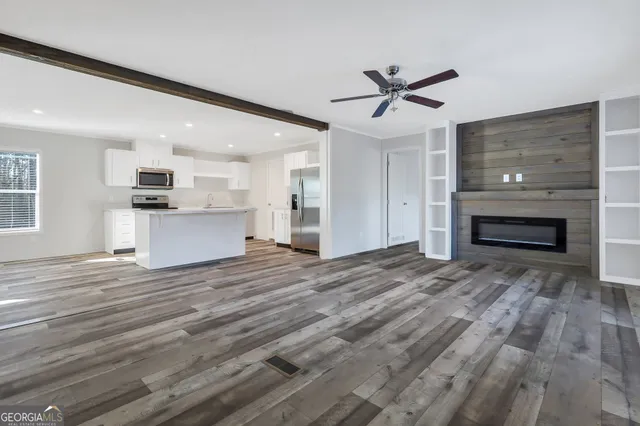 a view of empty room with kitchen and fireplace