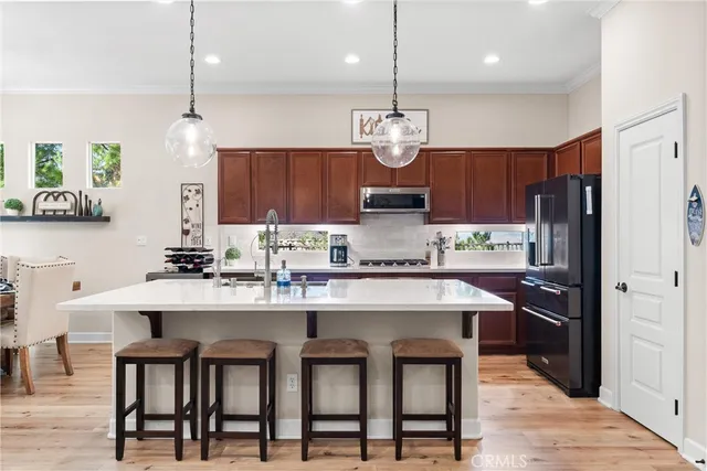 a kitchen with cabinets a sink stainless steel appliances and chairs