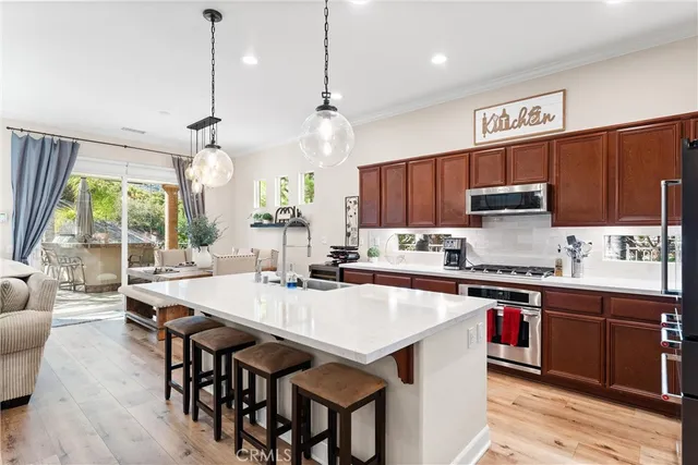 a kitchen with stainless steel appliances granite countertop a stove a refrigerator a sink dishwasher a dining table and chairs with wooden floor